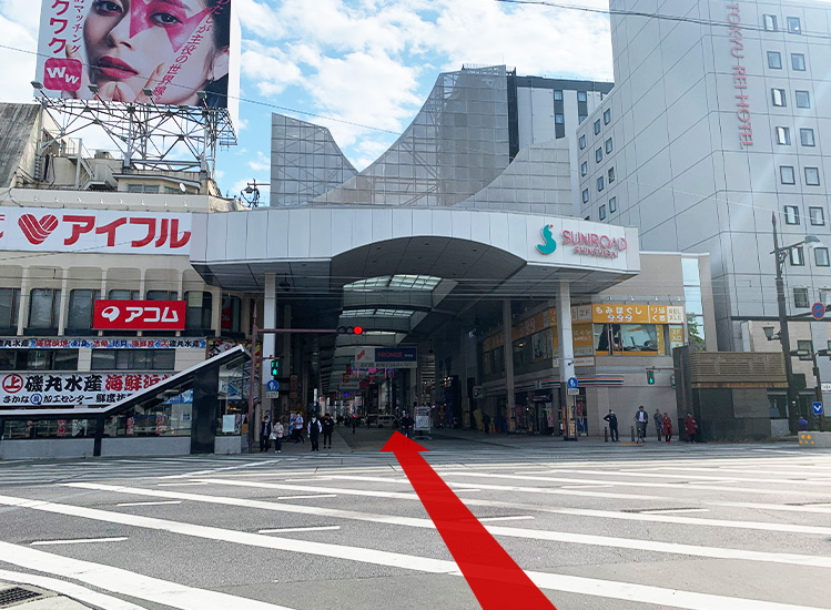 芝生を抜けると市電（路面電車）の辛島町駅（電停）がございます。その先に「サンロード新市街」という屋根付のアーケードがございますのでお入りください。